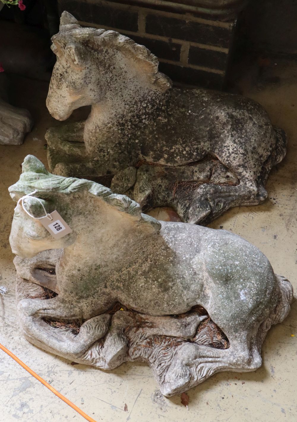 A pair of reconstituted stone recumbent horse garden ornaments, length 62cm